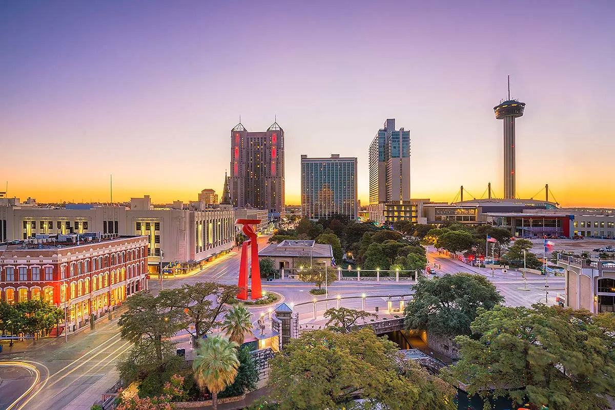 San Antonio skyline at sunset featuring the Tower of the Americas and Torch of Friendship sculpture, Texas cityscape view.